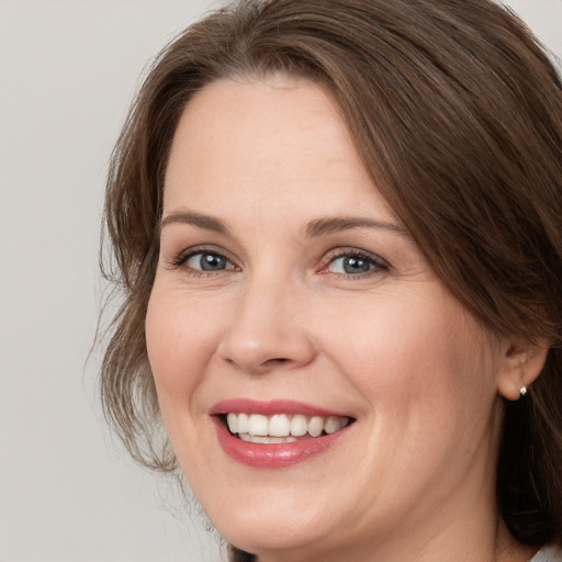 Joyful white adult female with medium  brown hair and grey eyes