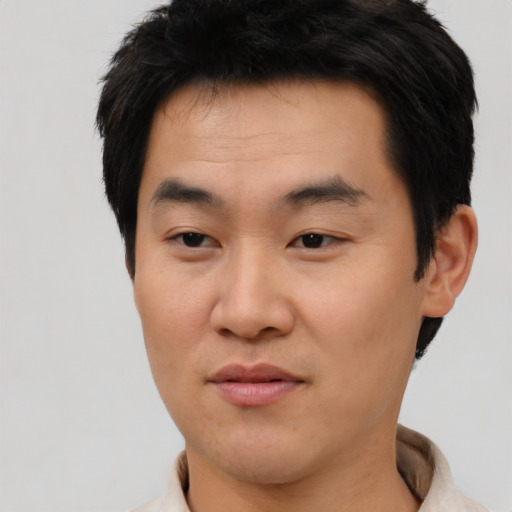 Joyful asian young-adult male with short  black hair and brown eyes