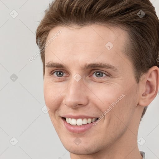 Joyful white young-adult male with short  brown hair and grey eyes