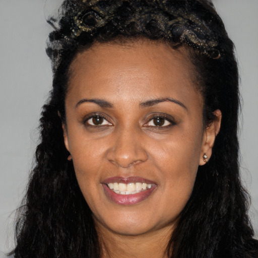 Joyful black young-adult female with long  black hair and brown eyes