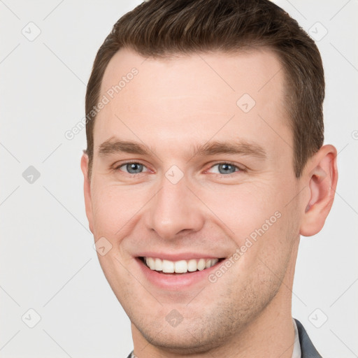 Joyful white young-adult male with short  brown hair and grey eyes