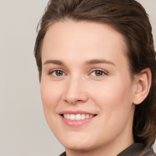 Joyful white young-adult female with medium  brown hair and grey eyes