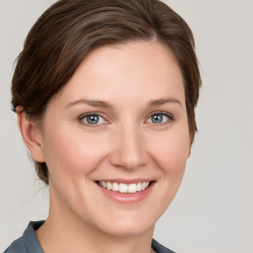 Joyful white young-adult female with medium  brown hair and grey eyes