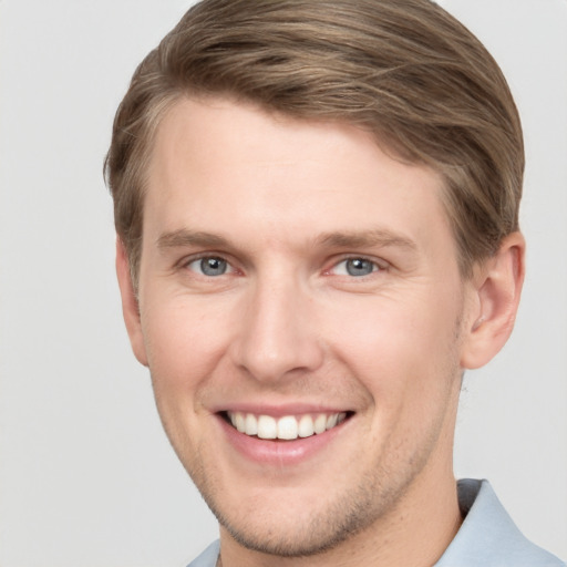 Joyful white young-adult male with short  brown hair and grey eyes