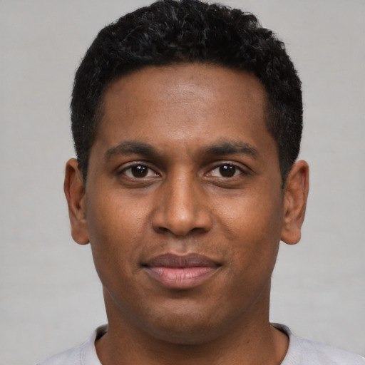Joyful black young-adult male with short  black hair and brown eyes