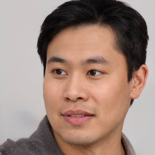 Joyful asian young-adult male with short  brown hair and brown eyes
