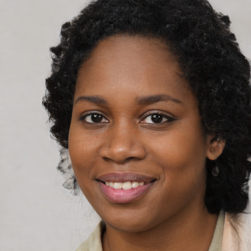 Joyful black young-adult female with long  black hair and brown eyes