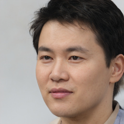 Joyful asian young-adult male with short  brown hair and brown eyes