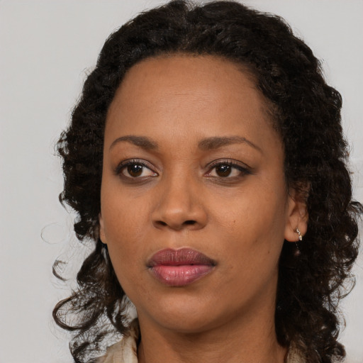 Joyful black adult female with long  brown hair and brown eyes