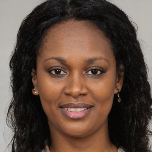 Joyful black young-adult female with long  brown hair and brown eyes