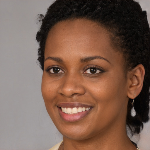 Joyful black young-adult female with long  brown hair and brown eyes