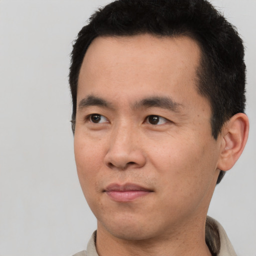 Joyful asian adult male with short  black hair and brown eyes