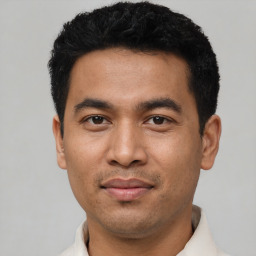 Joyful latino young-adult male with short  black hair and brown eyes