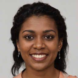 Joyful black young-adult female with long  brown hair and brown eyes