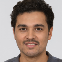 Joyful white young-adult male with short  black hair and brown eyes