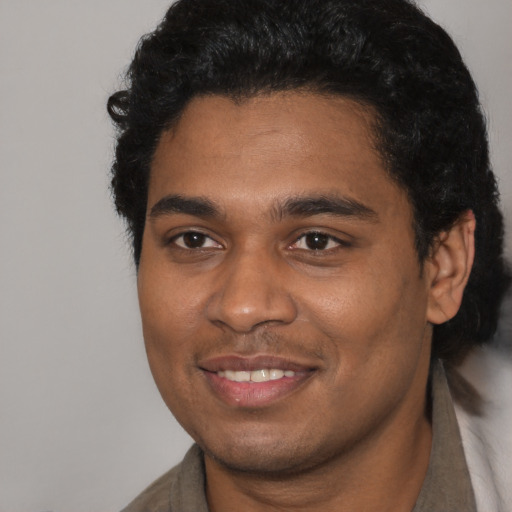Joyful black young-adult male with short  black hair and brown eyes