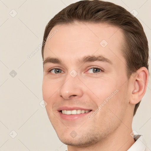 Joyful white young-adult male with short  brown hair and grey eyes