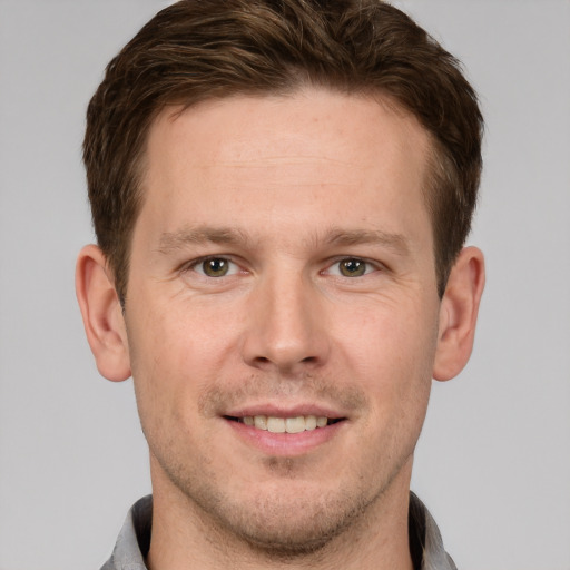 Joyful white young-adult male with short  brown hair and grey eyes