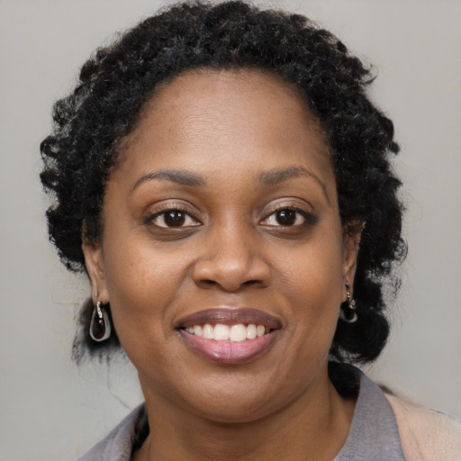 Joyful black young-adult female with short  black hair and brown eyes