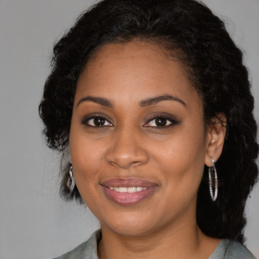 Joyful black young-adult female with long  brown hair and brown eyes