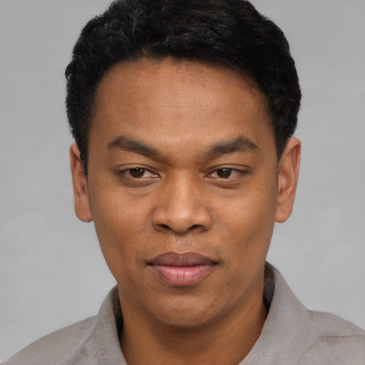 Joyful black young-adult male with short  black hair and brown eyes