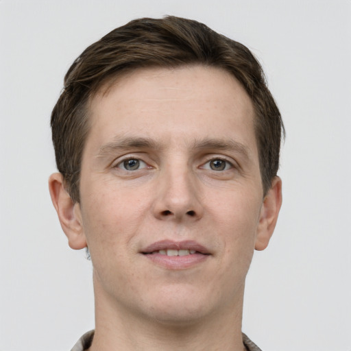 Joyful white young-adult male with short  brown hair and grey eyes