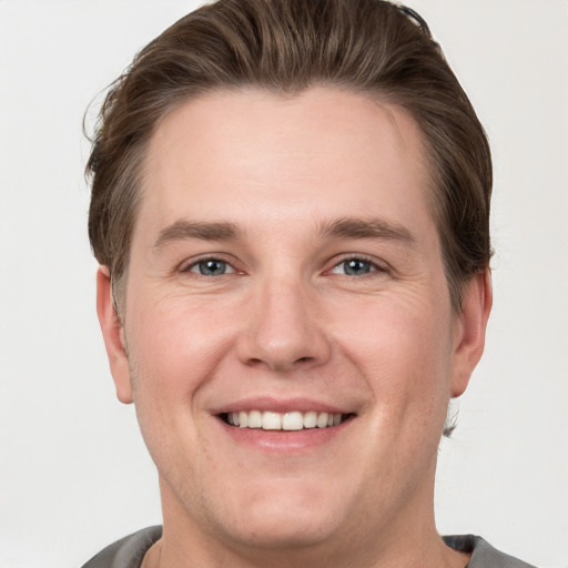 Joyful white young-adult male with short  brown hair and grey eyes