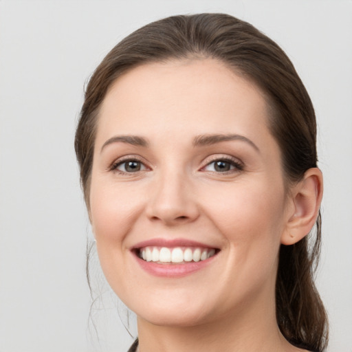 Joyful white young-adult female with medium  brown hair and grey eyes