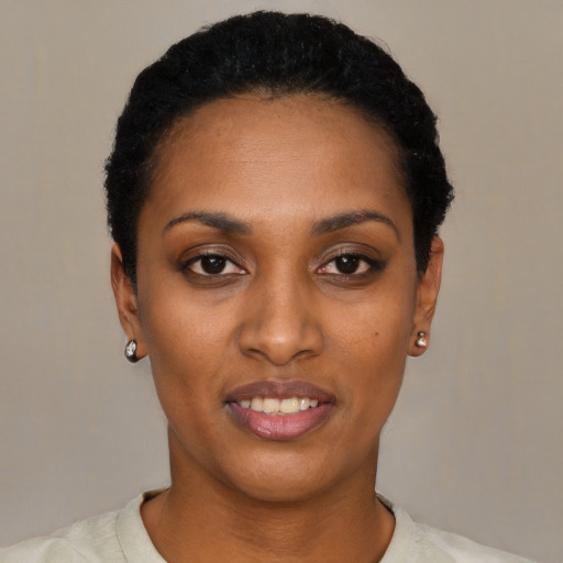 Joyful black young-adult female with short  black hair and brown eyes