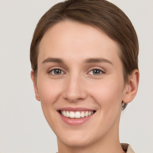 Joyful white young-adult female with short  brown hair and grey eyes