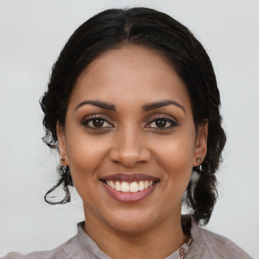 Joyful black young-adult female with long  black hair and brown eyes