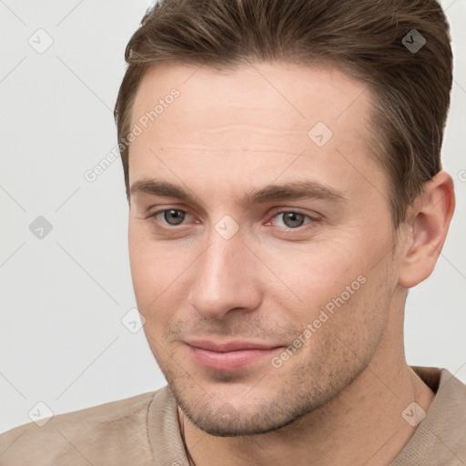 Joyful white young-adult male with short  brown hair and grey eyes