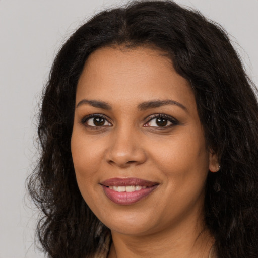 Joyful black young-adult female with long  brown hair and brown eyes