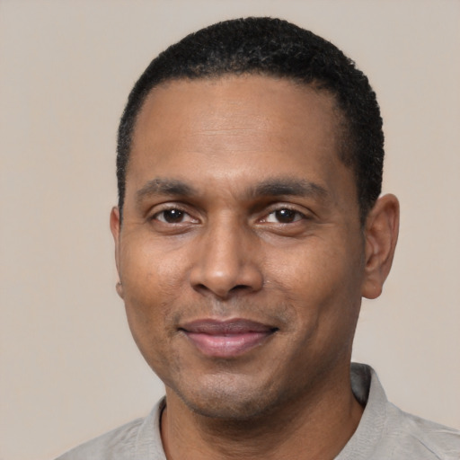 Joyful black young-adult male with short  black hair and brown eyes