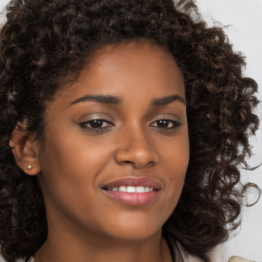 Joyful black young-adult female with long  brown hair and brown eyes