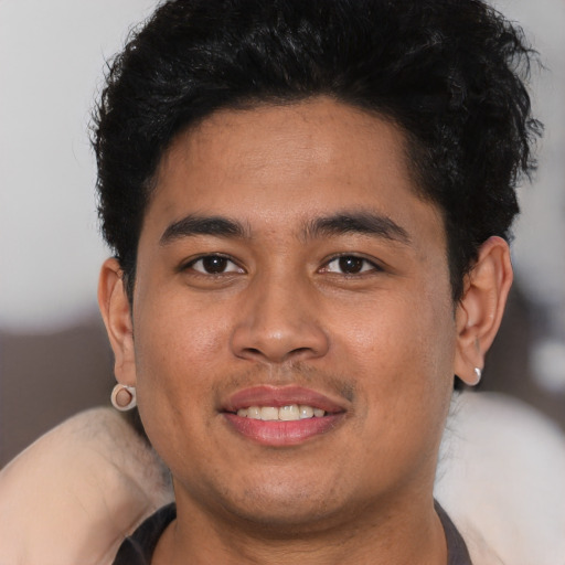 Joyful latino young-adult male with short  brown hair and brown eyes
