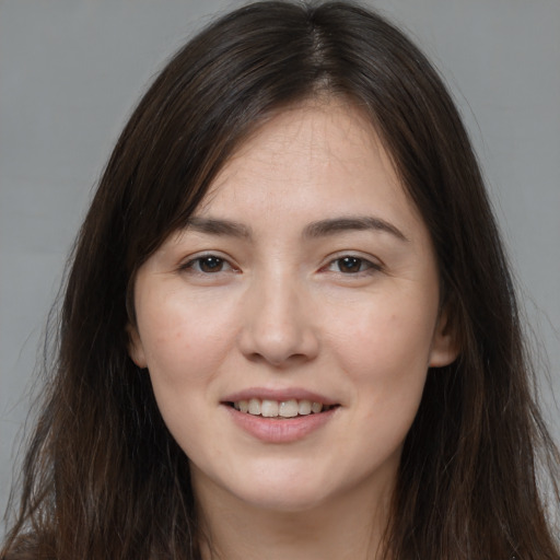 Joyful white young-adult female with long  brown hair and brown eyes