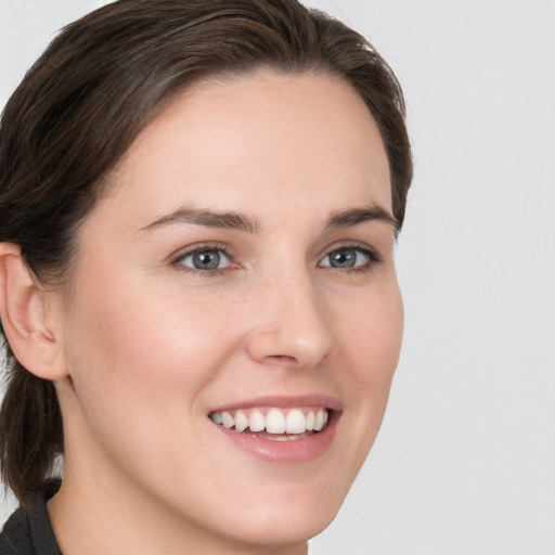 Joyful white young-adult female with medium  brown hair and grey eyes