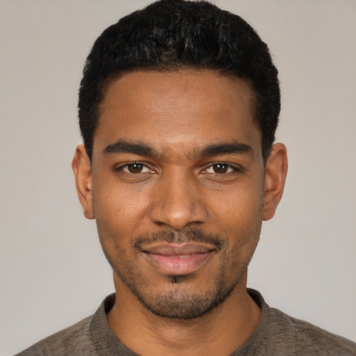 Joyful black young-adult male with short  black hair and brown eyes