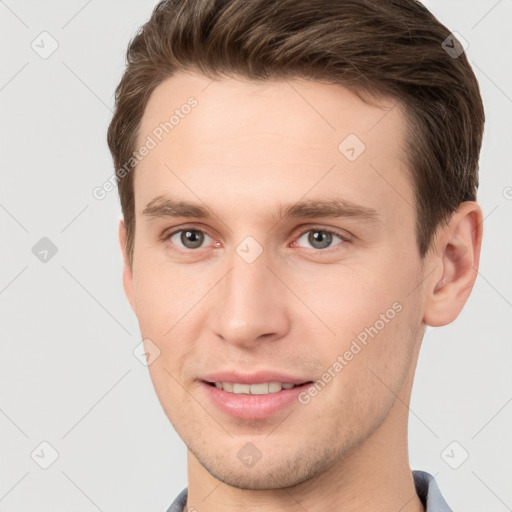 Joyful white young-adult male with short  brown hair and grey eyes