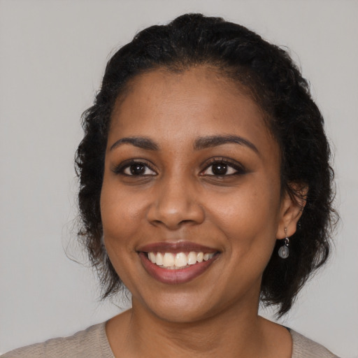 Joyful black young-adult female with medium  black hair and brown eyes