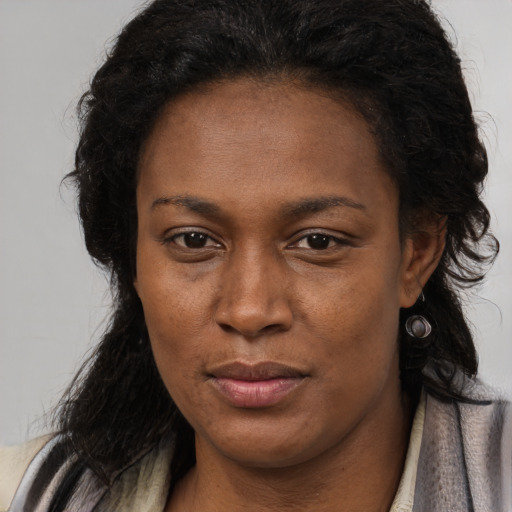 Joyful black young-adult female with long  brown hair and brown eyes