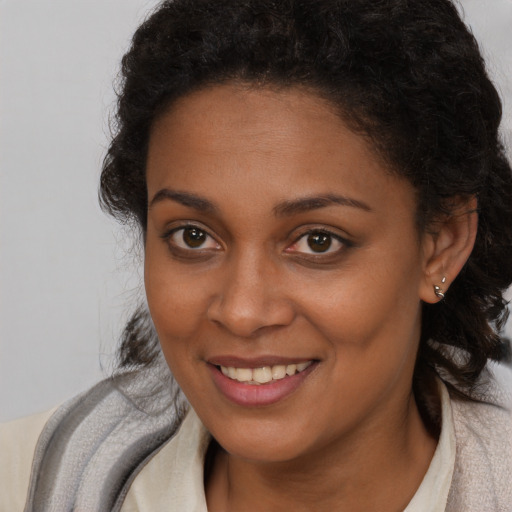 Joyful black young-adult female with long  brown hair and brown eyes