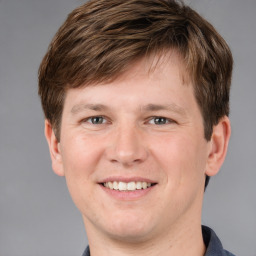 Joyful white young-adult male with short  brown hair and grey eyes