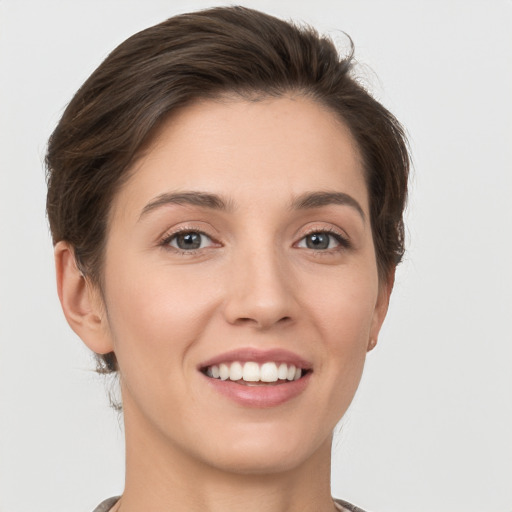 Joyful white young-adult female with short  brown hair and grey eyes