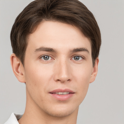 Joyful white young-adult male with short  brown hair and grey eyes