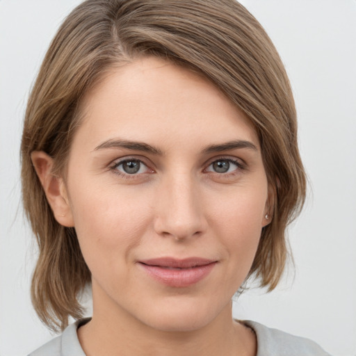 Joyful white young-adult female with medium  brown hair and grey eyes