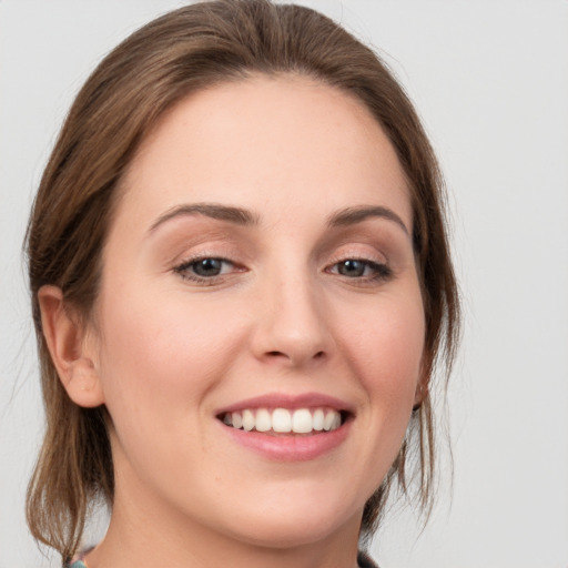 Joyful white young-adult female with medium  brown hair and grey eyes