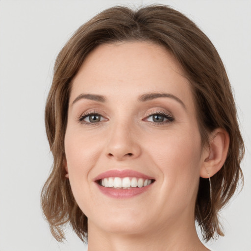 Joyful white young-adult female with medium  brown hair and green eyes