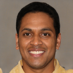 Joyful latino young-adult male with short  black hair and brown eyes